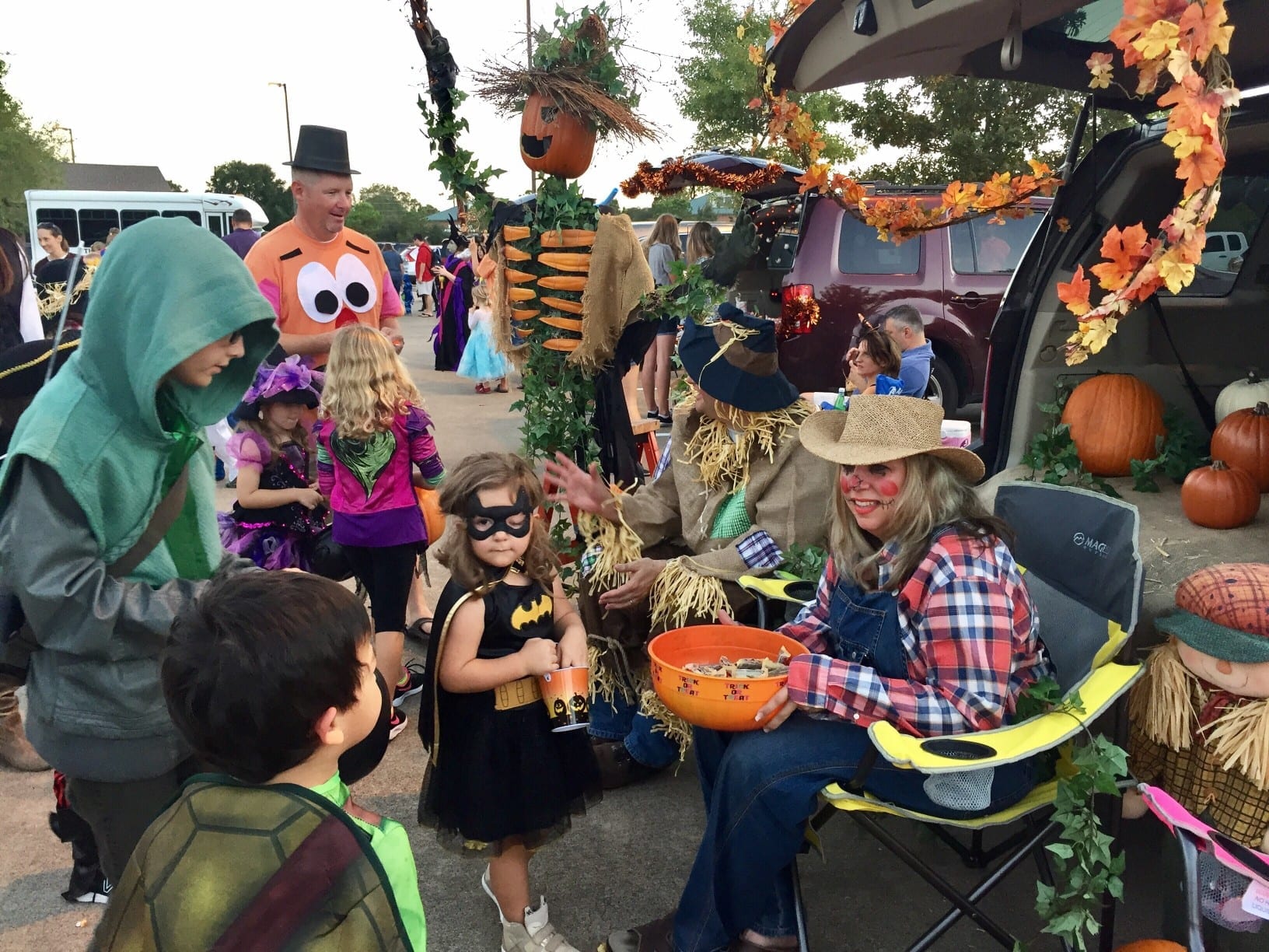 children receiving Halloween candy in costume at a Trunk or Treat event