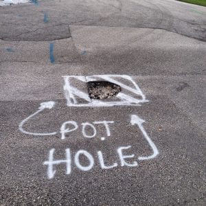 pothole in pavement marked with spray paint