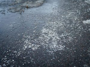 Ice melt dissolving ice on asphalt pavement