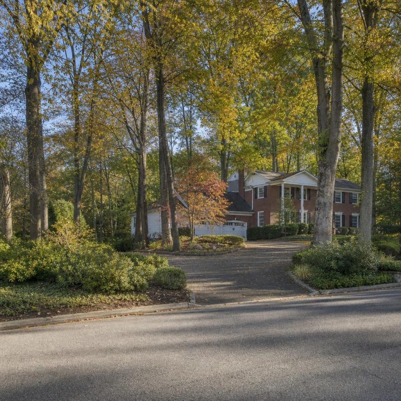 McLean residential street with detached homes, mature trees, wooded lots, and private driveways.